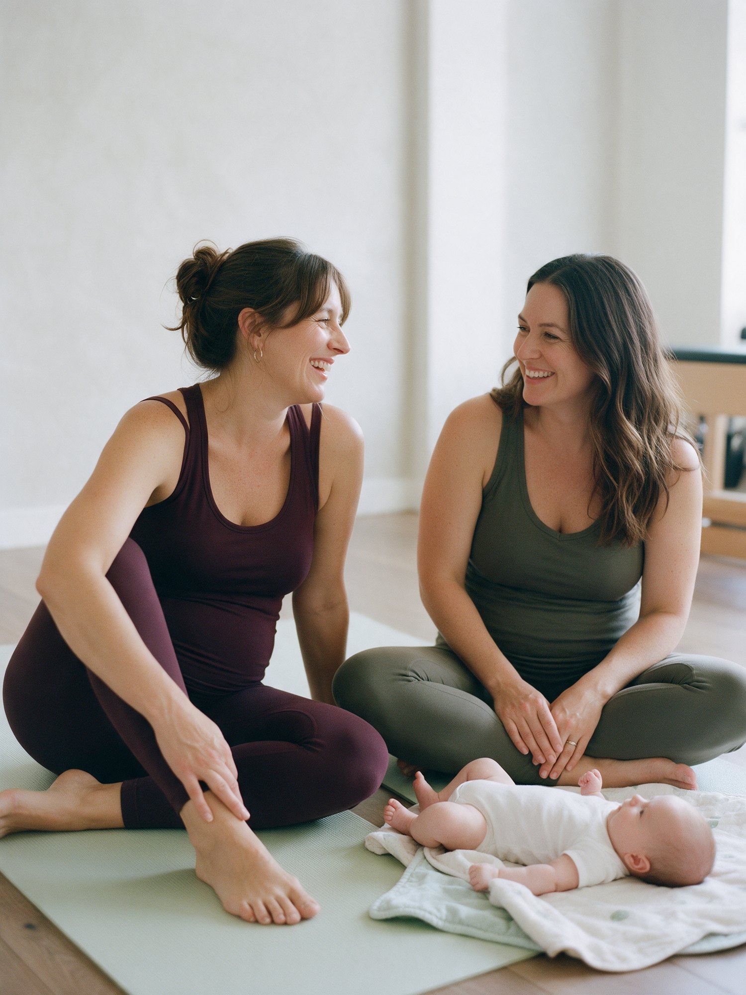 Illustrative image of two mothers chatting on separate studio mats with a baby nearby